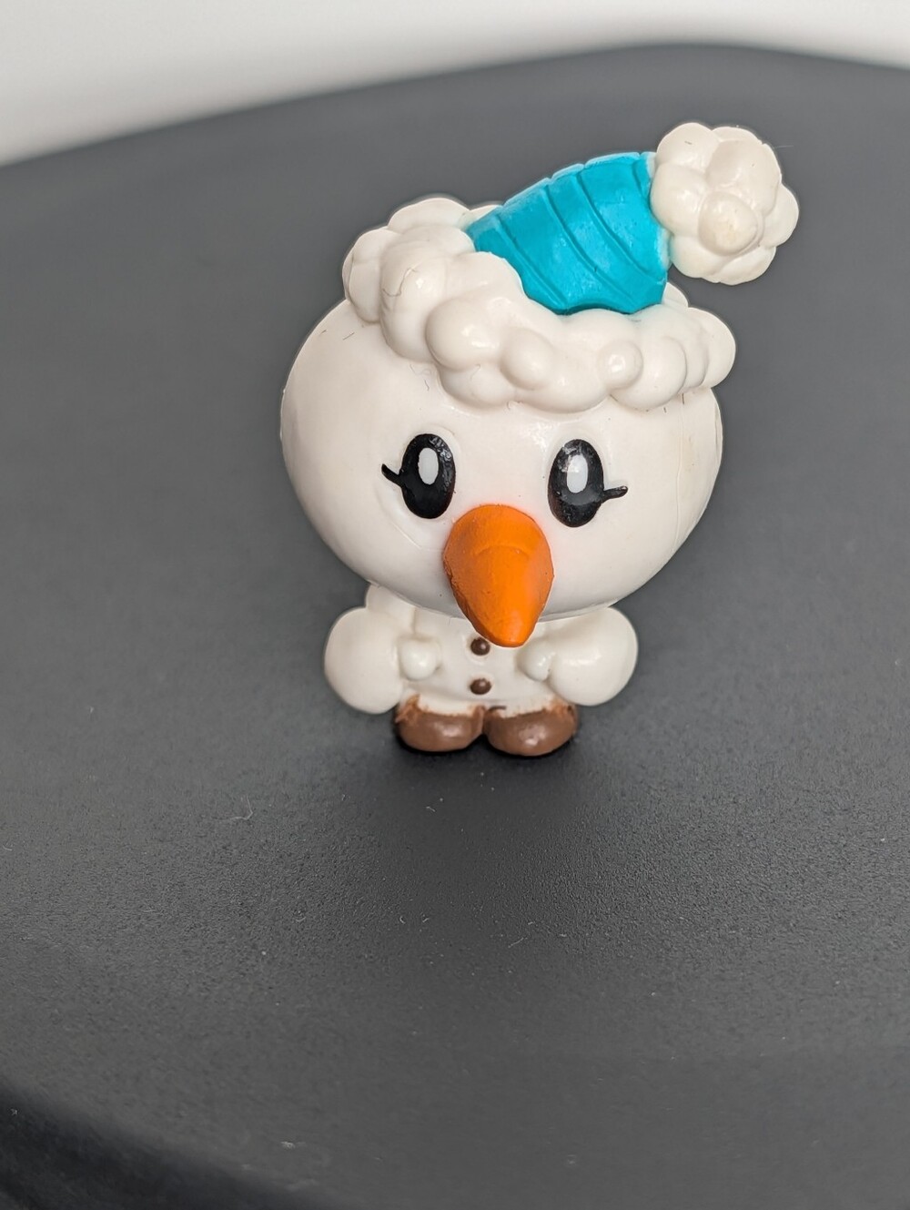 White snowman figurine with blue hat and orange carrot nose #snowman